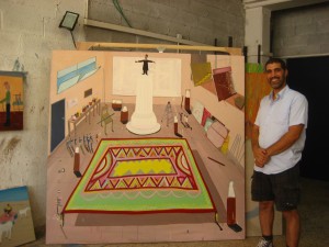 Shai in his studio with a painting depicting the many influences on the artist in his studio